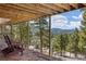 Inviting deck with Adirondack chairs showcases stunning mountain views through the lush evergreen trees at 6530 Ridgeview Dr, Morrison, CO 80465