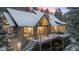 Stunning exterior view of a snow-covered mountain home, complemented by a spacious deck and stone accents at 6530 Ridgeview Dr, Morrison, CO 80465