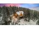 Stunning exterior view of cabin-style home nestled amongst the snowy forest at dusk at 6530 Ridgeview Dr, Morrison, CO 80465