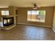 This vacant living room features a fireplace, ceiling fan, tile floors, and a large window overlooking the yard at 20787 E 39Th Ave, Denver, CO 80249