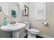 Elegant powder room with a pedestal sink, round mirror, and white wood blinds at 2716 N Columbine St, Denver, CO 80205