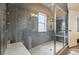 Clean bathroom featuring an enclosed shower with grey tiling, a bright window, and a white elongated toilet at 2716 N Columbine St, Denver, CO 80205