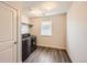 Well-lit laundry room with dark-colored washer and dryer and wood-look flooring at 4327 Wilson Peak Dr, Castle Rock, CO 80104