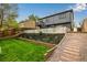 An inviting backyard with a retaining wall, steps, landscaped area, and green lawn at 19661 E Girard Ave, Aurora, CO 80013