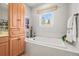 Relaxing bathroom featuring a soaking tub under a window, flanked by stylish wood cabinets and decor at 20957 Horse Bit Way, Morrison, CO 80465
