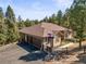 Exterior view with a three-car garage, manicured lawn, Colorado flag, and mature trees at 20957 Horse Bit Way, Morrison, CO 80465