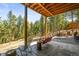 Relaxing covered patio with a porch swing overlooking a serene wooded area at 20957 Horse Bit Way, Morrison, CO 80465