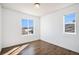 Bright bedroom featuring wood-look floors, two large windows, and fresh white walls at 5367 Spring Ridge Trl, Castle Rock, CO 80104