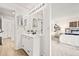 Modern bathroom with white cabinets, dual mirrors, and open view to the primary bedroom at 10311 E Evans Ave # 132, Aurora, CO 80247