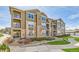 View of a three-story condominium complex with brown siding, stone accents, and well-maintained landscaping at 2855 Blue Sky Cir # 3-102, Erie, CO 80516