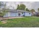Back exterior of a light blue home with a patio, lawn, and mature trees at 17731 E Bails Pl, Aurora, CO 80017