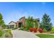Beautifully landscaped home with stone accents and a lush front yard featuring colorful shrubs and a curved driveway at 5608 Raintree Dr, Parker, CO 80134