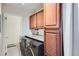 A laundry room with granite countertops, wooden cabinets, and modern washer and dryer at 6021 Yarrow St # B13, Arvada, CO 80004