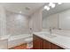 A bright bathroom features a tub with tile surround, modern vanity, and hexagon tile floors at 2466 S Cherokee St, Denver, CO 80223