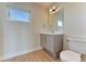 Bathroom featuring modern vanity, toilet, and a well-lit mirror with a small window for natural light at 2466 S Cherokee St, Denver, CO 80223