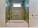 A green-tiled bathtub with a showerhead, and a small window at 2466 S Cherokee St, Denver, CO 80223