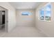 An empty bedroom with neutral carpet, two windows, and an en-suite bathroom at 2466 S Cherokee St, Denver, CO 80223