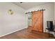 Bedroom featuring a hardwood floor, ceiling fan, and a stylish rustic barn door at 9235 Quintero St, Commerce City, CO 80022