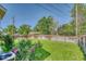 Spacious backyard with a well-maintained lawn, a wooden fence, mature trees, and vibrant pink roses in the foreground at 3100 S Corona St, Englewood, CO 80113