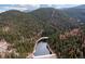 Panoramic aerial view of a lake nestled in a valley of dense, green forests at 1264 Beaver Brook Canyon Rd, Evergreen, CO 80439