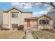 Charming tan two-story home with an orange front door and a well-manicured lawn with mature trees at 4314 Nepal St, Denver, CO 80249