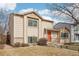 Charming tan two-story home with an orange front door and a well-manicured lawn with mature trees at 4314 Nepal St, Denver, CO 80249