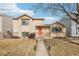 Charming tan two-story home with an orange front door and a well-manicured lawn with mature trees at 4314 Nepal St, Denver, CO 80249