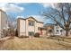 Charming tan two-story home with an orange front door and a well-manicured lawn with mature trees at 4314 Nepal St, Denver, CO 80249