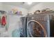 Functional laundry room with modern washer and dryer units, and storage shelves at 4314 Nepal St, Denver, CO 80249