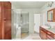 Bright bathroom with a glass walk-in shower, cherry wood vanity and white hexagon tile flooring at 3328 Bryant St, Denver, CO 80211