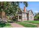 Charming home with a manicured lawn, wrought iron fence, brick chimney, and mature trees on a sunny day at 3328 Bryant St, Denver, CO 80211