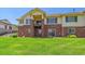 Back exterior featuring a brick and siding facade, walkout basement and lush lawn at 7912 S Buchanan Way, Aurora, CO 80016