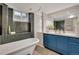 Elegant bathroom with a soaking tub, blue vanity, and a large mirror at 9400 Ridge Rd, Arvada, CO 80002