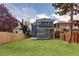Spacious, fenced backyard with lush green grass, mature trees, and a quaint deck at 1050 N Clarkson St, Denver, CO 80218