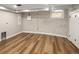 Spacious basement area with exposed brick wall, a drop ceiling, and hardwood-style flooring at 1050 N Clarkson St, Denver, CO 80218