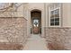 Inviting front entrance with a charming wooden door, stone accents, and an elegant arched entryway at 1039 Buffalo Ridge Way, Castle Pines, CO 80108