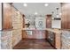 Close-up of the wet bar with stone accents, wood cabinets, hardwood floor, and pendant lights at 1039 Buffalo Ridge Way, Castle Pines, CO 80108