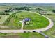 Aerial view of gray two-story home with solar panels on a large lot surrounded by green fields at 43793 Buckskin Rd, Parker, CO 80138