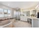 Bright bathroom featuring a soaking tub, glass shower, and vanity with ample counter space at 15573 E Prentice Ln, Centennial, CO 80015