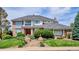 Beautiful brick home with a well-maintained lawn, brick stairs, and a red front door at 15573 E Prentice Ln, Centennial, CO 80015