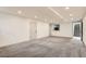 Open basement space featuring neutral walls, gray carpet, recessed lights, and access to the stairs and kitchen at 3361 S Dahlia St, Denver, CO 80222