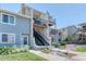 A well-maintained condo exterior featuring upper and lower-level patios, a stairway, and tidy landscaping at 6007 Yarrow St # D, Arvada, CO 80004