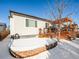 Backyard featuring a wood deck with pergola and a brick patio in a snow-covered yard at 6308 Walnut Grove Way, Erie, CO 80516