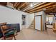 Unfinished basement with exposed ceiling beams, a chair and a small staircase at 1346 Steele St, Denver, CO 80206