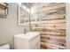 Bathroom featuring wood accent wall, modern mirror, white sink, and cabinet at 13158 W 62Nd Dr, Arvada, CO 80004