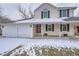 Welcoming two-story home featuring a covered front porch, red door, and three car garage at 13158 W 62Nd Dr, Arvada, CO 80004