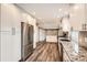 Bright kitchen with stainless steel refrigerator, white cabinets, wood floors, and granite countertops at 13158 W 62Nd Dr, Arvada, CO 80004