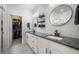 Bathroom featuring double sinks with dark countertops, white cabinets, and modern lighting fixtures at 11524 Dewey St, Parker, CO 80138