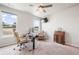 Bright bedroom featuring carpeted floors, two windows, a ceiling fan, and a desk area at 11524 Dewey St, Parker, CO 80138