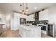 Bright kitchen features an island, stainless appliances, and sleek white cabinets with elegant lighting fixtures at 11524 Dewey St, Parker, CO 80138
